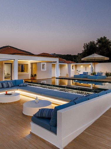 Villa exterior, pool, and outdoor sitting area at dusk