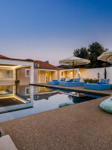 Villa exterior, pool, and sunbeds at dusk